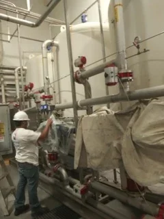 Painter applying coating to industrial metal pipes and equipment in commercial facility