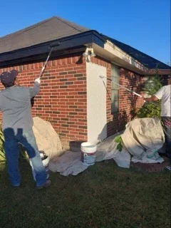 Brick house exterior with freshly painted white trim and roof edge against clear sky