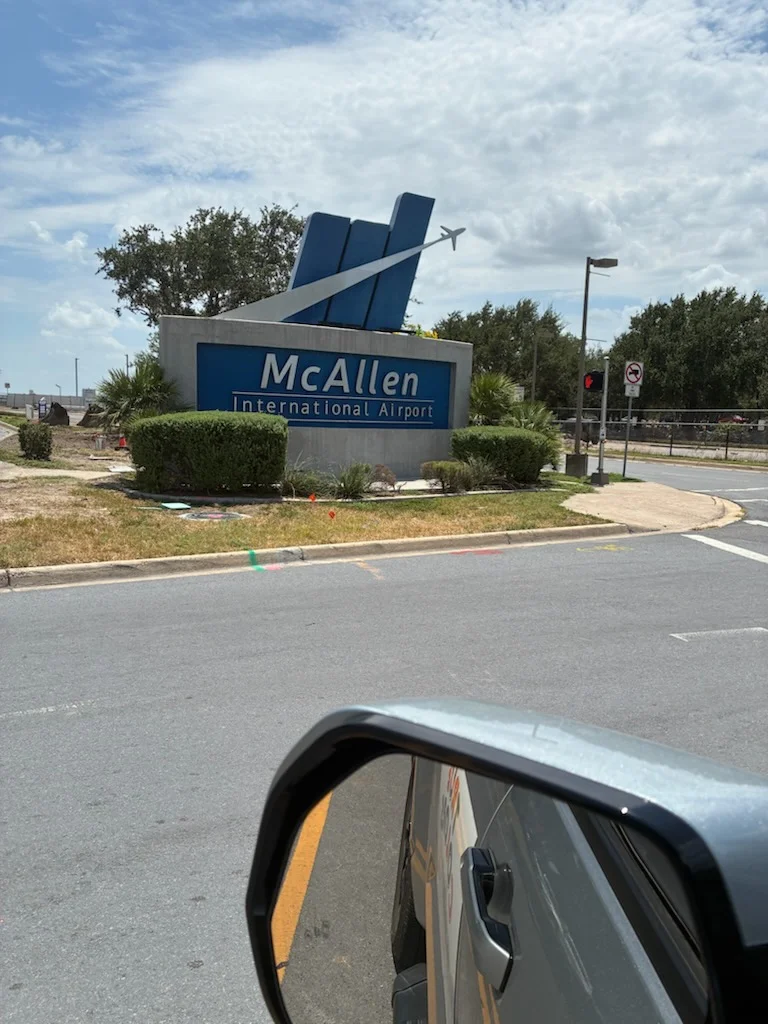 Large blue and white airport sign with airplane graphic, freshly painted blue panels and white trim