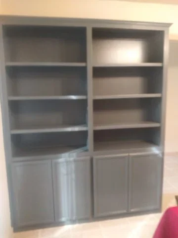 Gray painted built-in shelving unit with white cabinet doors and open shelves