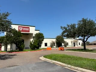 White commercial building with red signage band, freshly painted exterior walls and trim