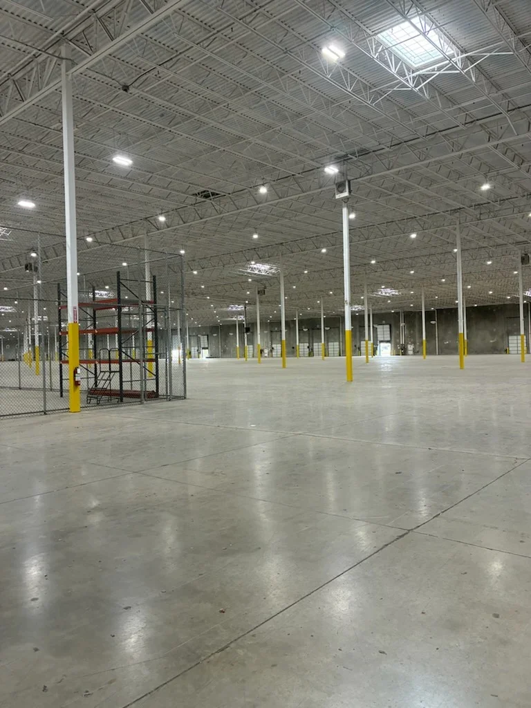 Painted concrete warehouse floor and ceiling with steel support columns and LED lighting