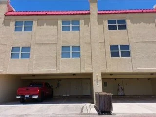 Multi-story commercial building with freshly painted stucco exterior and red metal roof