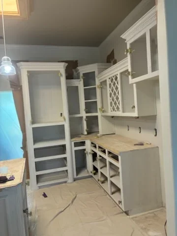 White painted pantry cabinetry with glass doors, open shelving, and built-in counter workspace