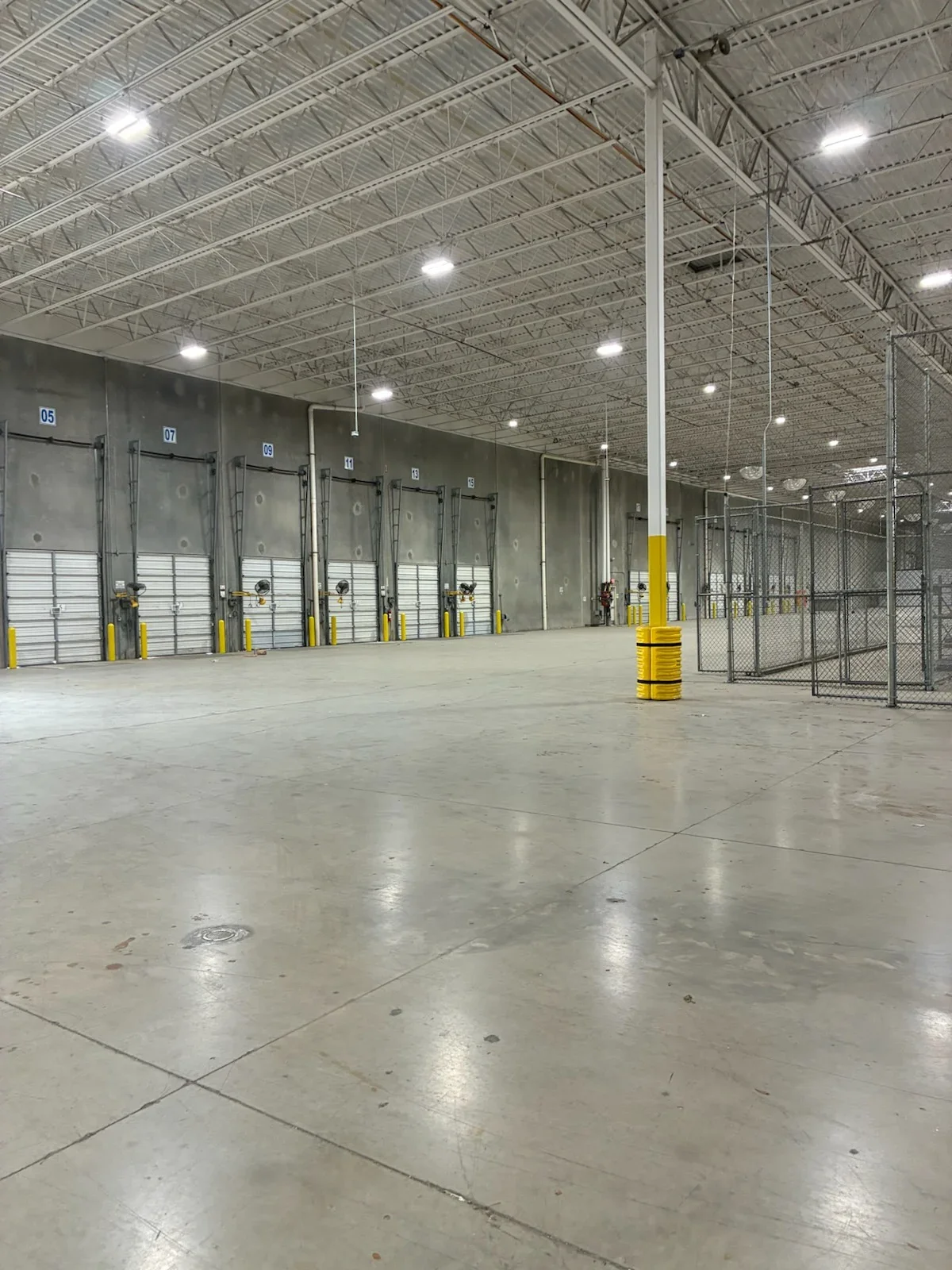 Industrial warehouse with gray painted loading dock doors, polished concrete floor, and LED ceiling lights