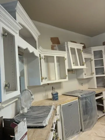 White painted kitchen cabinets with glass doors and trim work during refinishing project