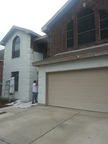 Two-story home with white stucco and brick exterior, freshly painted trim and siding