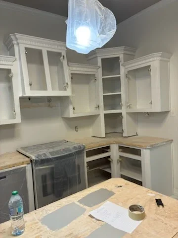 White painted kitchen cabinets with glass doors and open shelving, pendant light fixture overhead