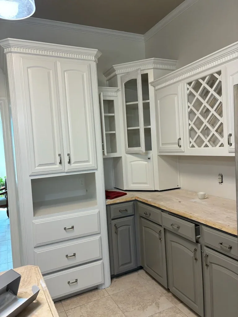 Two-tone kitchen cabinets with white upper and gray lower units, decorative lattice doors, and trim work