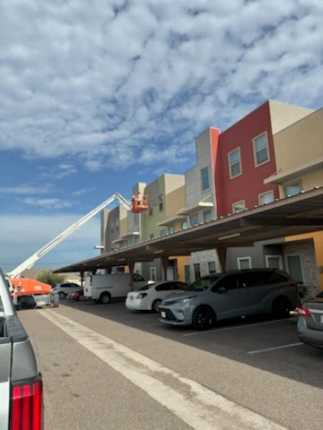 Multi-story commercial building with red and tan exterior paint, covered parking area below