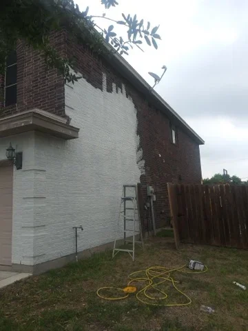 White painted wood siding and brick exterior on residential home during painting project