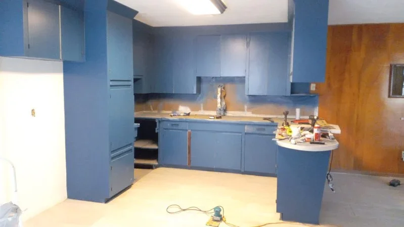 Blue painted kitchen cabinets and walls with island and countertops