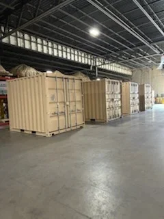 Industrial warehouse floor with concrete surface preparation and staged materials in containers