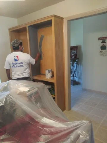 Painter applying paint to wooden closet doors and interior walls during residential painting project